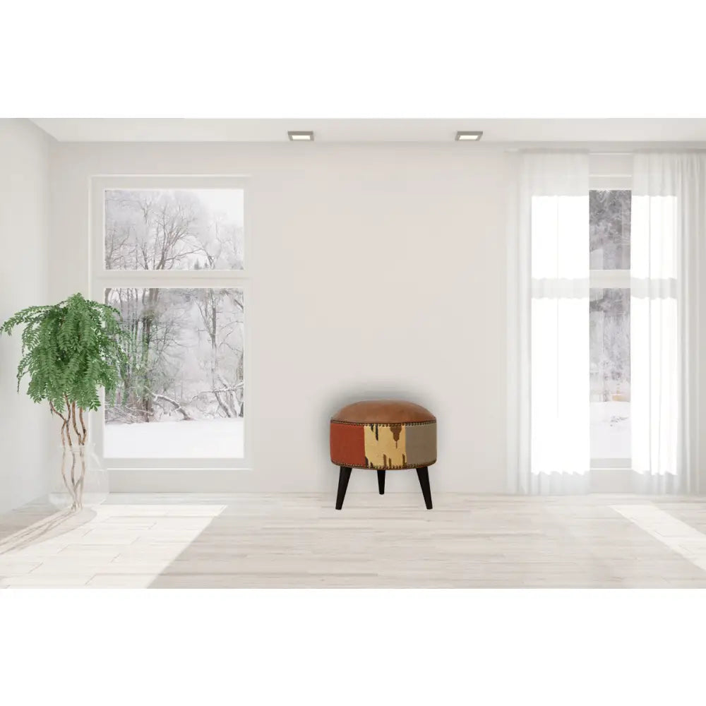 Durrie & Leather Mixed Footstool with Nordic-style legs, buffalo leather, and durrie print. Footstool positioned in a living space.